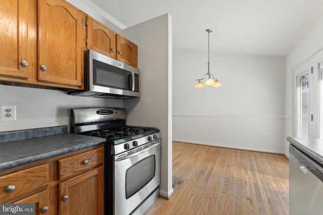 11505 Brian Dr, Fredericksburg, VA 22407 - kitchen featuring stainless steel appliances, brown cabinetry, light wood-style flooring, dark countertops, and pendant lighting