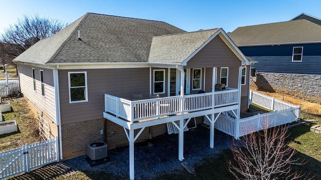 rear view of house with a fenced backyard, central air condition unit, a wooden deck, and roof with shingles