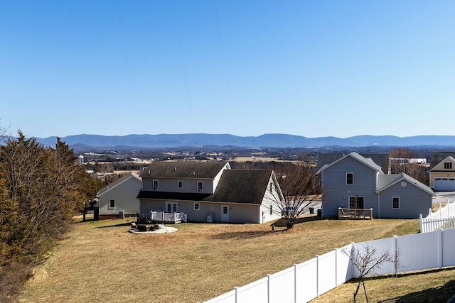 back of property with a lawn, a mountain view, and a fenced backyard