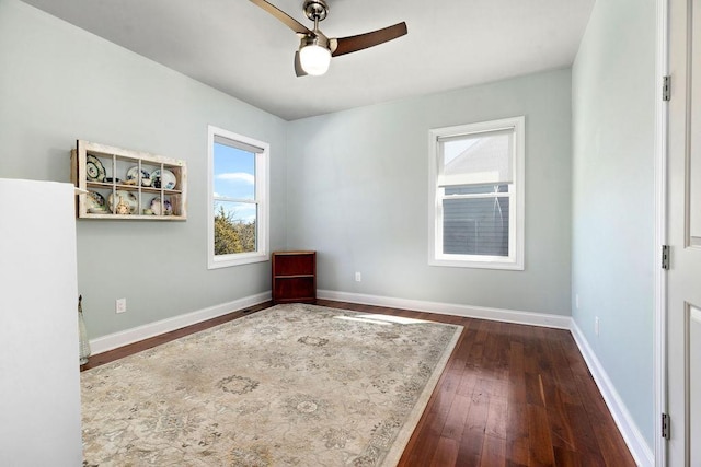 interior space featuring a ceiling fan, baseboards, and wood-type flooring