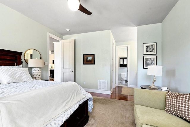 bedroom featuring wood finished floors, visible vents, baseboards, ceiling fan, and ensuite bathroom