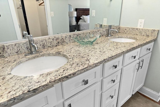 bathroom with a sink, baseboards, wood finished floors, and double vanity