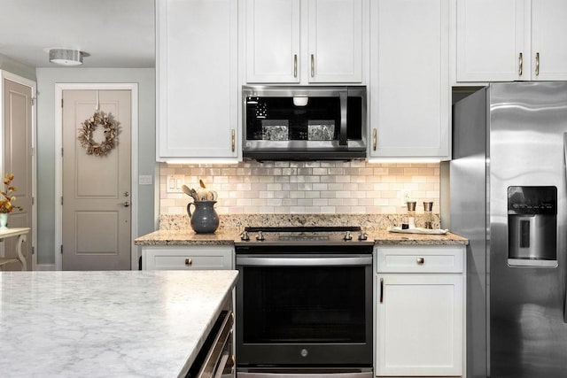 kitchen featuring light stone counters, decorative backsplash, white cabinets, and stainless steel appliances