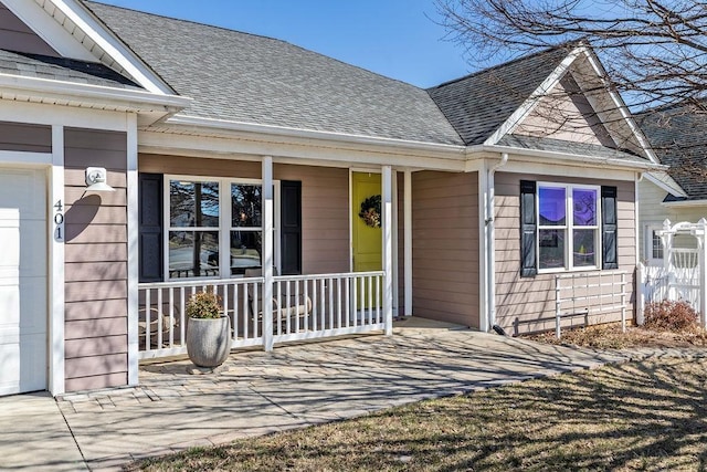 property entrance with a porch, an attached garage, and a shingled roof