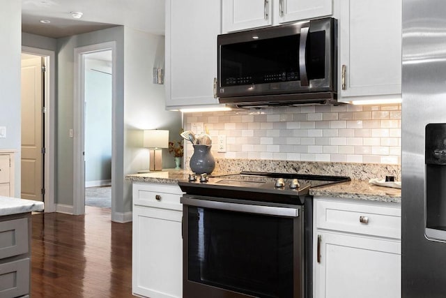 kitchen featuring backsplash, dark wood finished floors, appliances with stainless steel finishes, baseboards, and light stone countertops