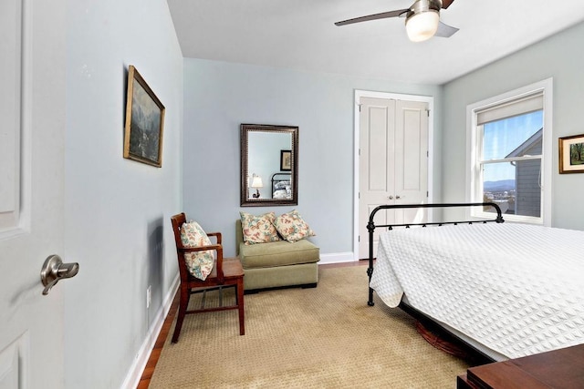 bedroom with a closet, ceiling fan, light carpet, and baseboards