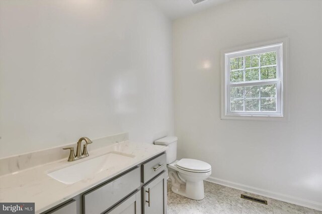 half bathroom featuring toilet, vanity, and baseboards