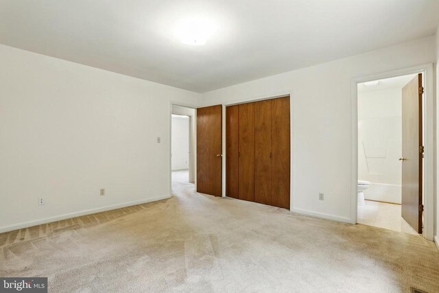 unfurnished bedroom with carpet, baseboards, a closet, and ensuite bathroom