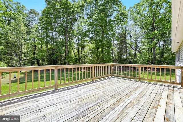 wooden deck featuring a yard and view of wooded area