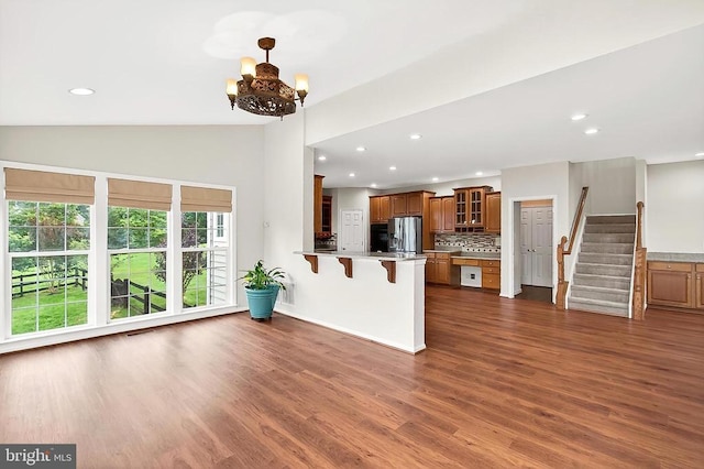  - kitchen featuring stainless steel fridge, brown cabinets, a peninsula, glass insert cabinets, and a kitchen bar