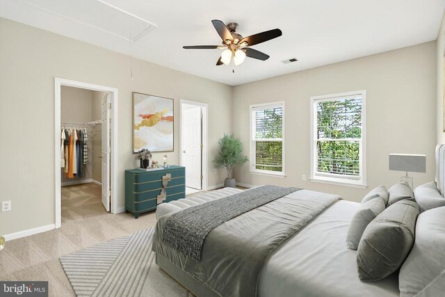  - bedroom featuring attic access, light colored carpet, a spacious closet, and ceiling fan