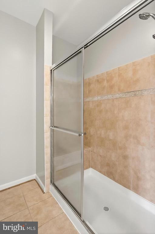  - bathroom featuring a tile shower and tile patterned flooring