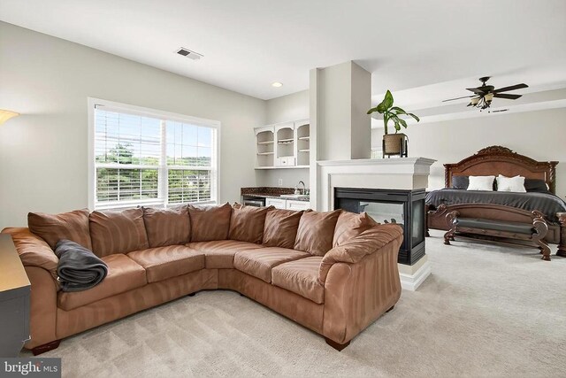  - living room featuring light colored carpet, ceiling fan, and a multi sided fireplace