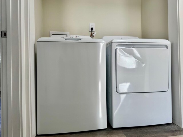 clothes washing area with dark hardwood / wood-style floors and washing machine and dryer