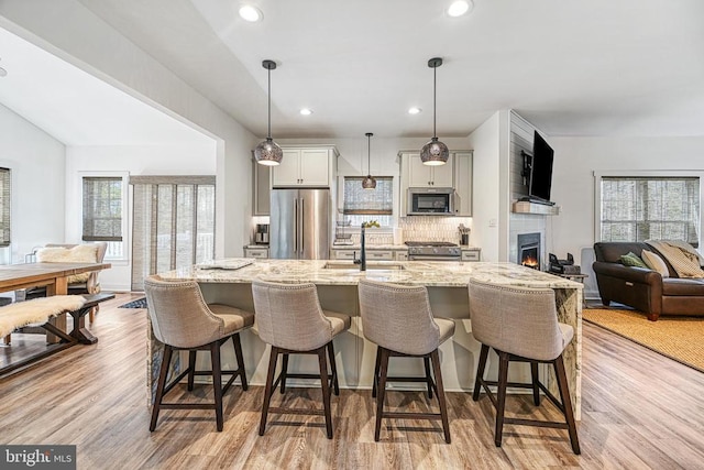 295 Hemlock Loop, Mineral, VA 23117 - kitchen with premium appliances, a sink, decorative backsplash, a breakfast bar, and a large fireplace