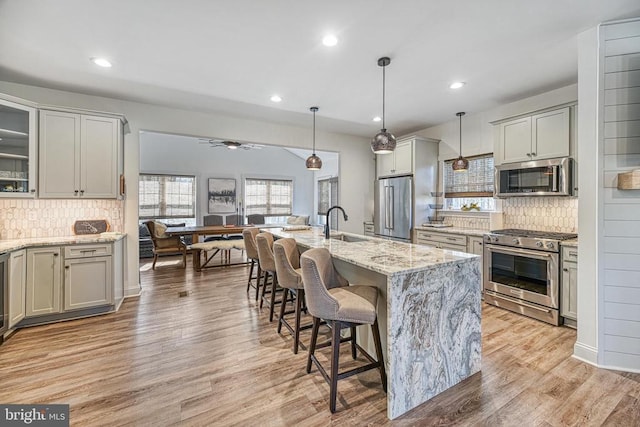 295 Hemlock Loop, Mineral, VA 23117 - kitchen featuring premium appliances, decorative backsplash, light stone countertops, a sink, and a breakfast bar area