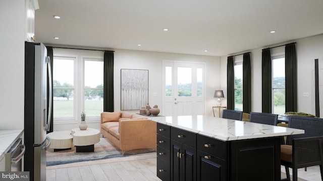  - kitchen featuring dark cabinets, open floor plan, stainless steel appliances, a kitchen breakfast bar, and light wood-type flooring
