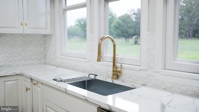  - kitchen with white cabinets, backsplash, and healthy amount of natural light
