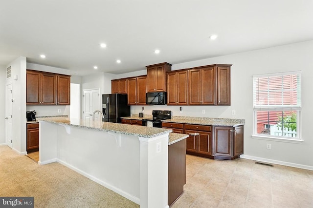  - kitchen featuring black appliances, an island with sink, recessed lighting, light stone counters, and a breakfast bar