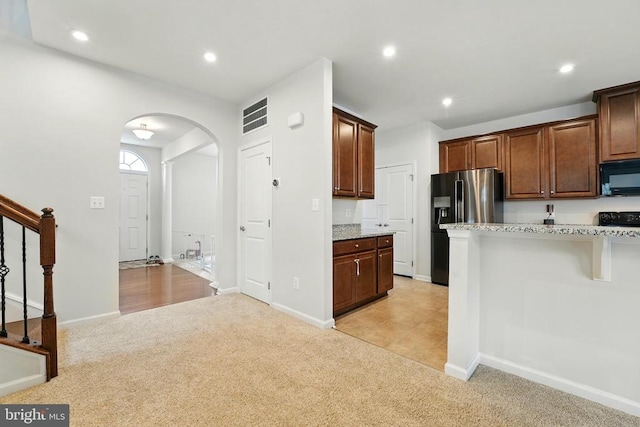  - kitchen with black microwave, light colored carpet, range, arched walkways, and recessed lighting