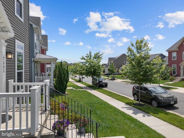  - view of green lawn featuring covered porch and a residential view