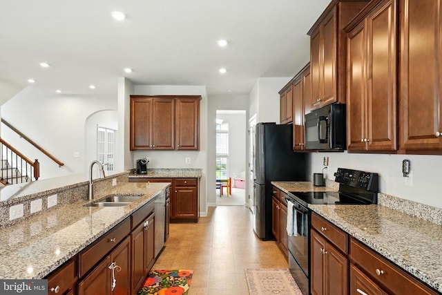  - kitchen with black appliances, light stone countertops, arched walkways, and recessed lighting