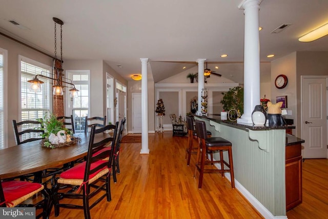 dining room featuring light wood finished floors, visible vents, and ornate columns