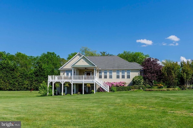 back of property with a ceiling fan, a yard, and stairway