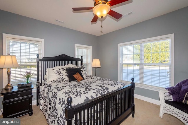 bedroom with light carpet, visible vents, and multiple windows