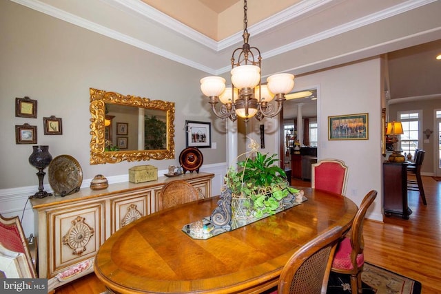 dining space with crown molding, wood finished floors, and a notable chandelier