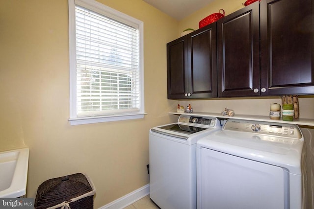 clothes washing area with washing machine and clothes dryer, cabinet space, and baseboards