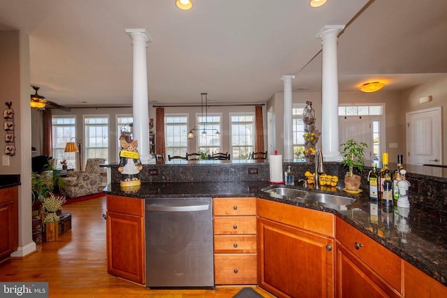 kitchen with a sink, stainless steel dishwasher, a wealth of natural light, and ornate columns