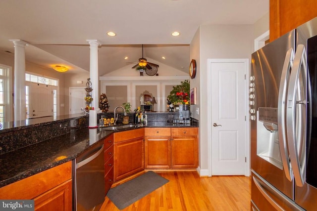 kitchen with a sink, stainless steel appliances, decorative columns, light wood-type flooring, and a ceiling fan
