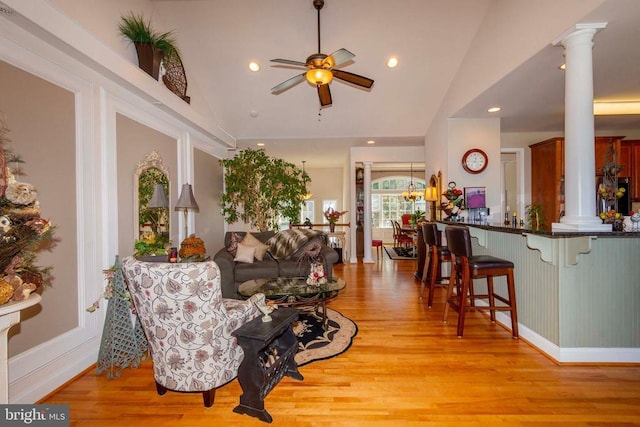 living room with ceiling fan, vaulted ceiling, light wood-style flooring, and ornate columns