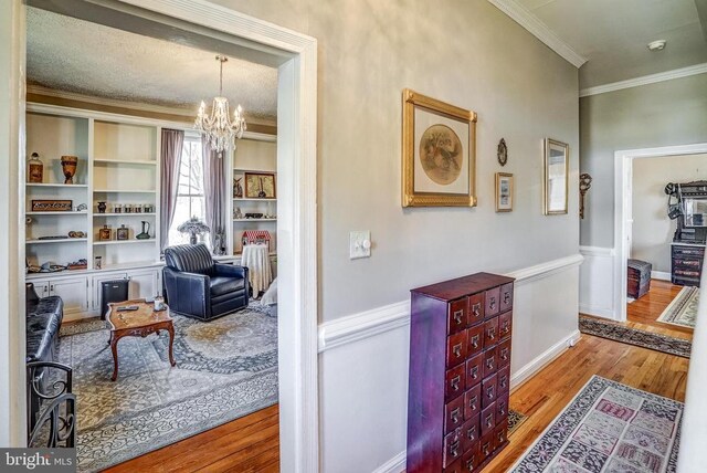 215 Fredericksburg Ave, Louisa, VA 23093 - hallway with an inviting chandelier, wood finished floors, a wainscoted wall, and ornamental molding