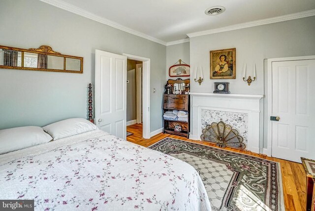 215 Fredericksburg Ave, Louisa, VA 23093 - bedroom with visible vents, a fireplace, crown molding, light wood finished floors, and baseboards