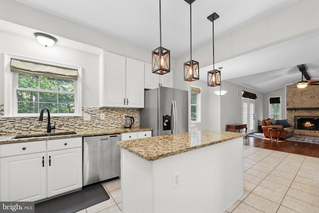 2357 Brighton Pl, Jeffersonton, VA 22724 - kitchen featuring appliances with stainless steel finishes, light tile patterned floors, a center island, a brick fireplace, and light stone counters