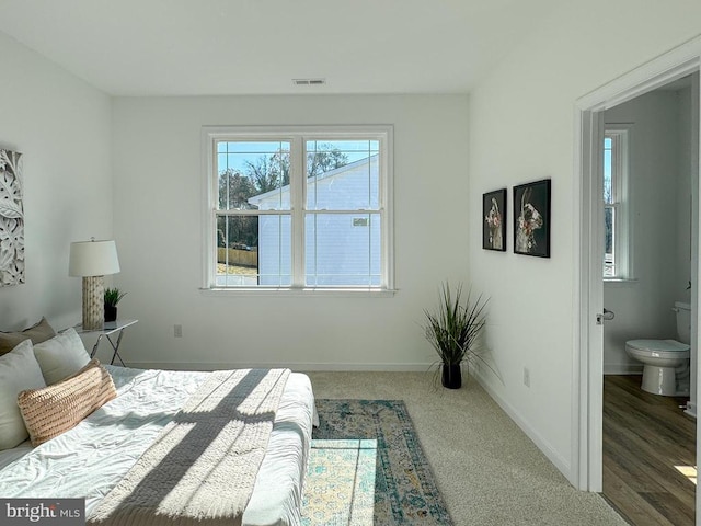 bedroom with baseboards, visible vents, and ensuite bathroom