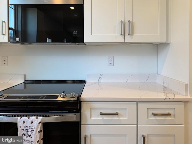 kitchen featuring light stone counters, electric range oven, and white cabinets