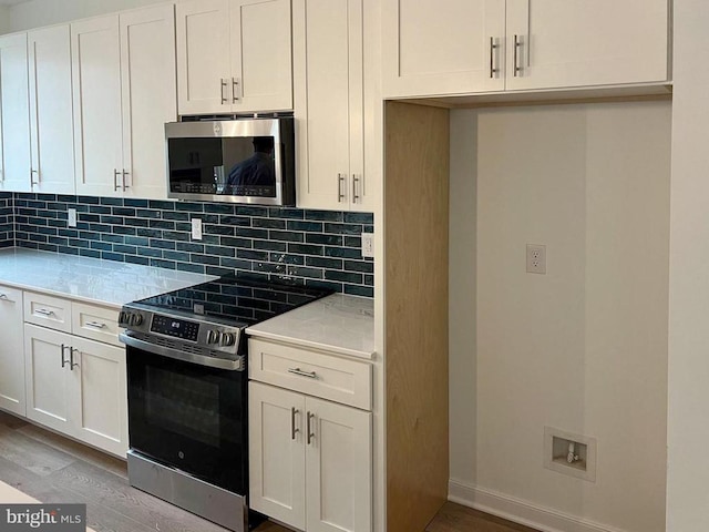 kitchen with light wood-style floors, tasteful backsplash, stainless steel appliances, and light countertops