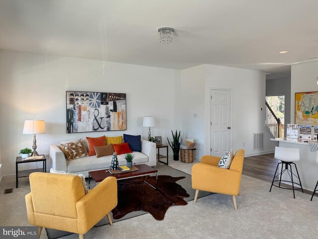 living room featuring carpet floors, baseboards, stairs, and visible vents