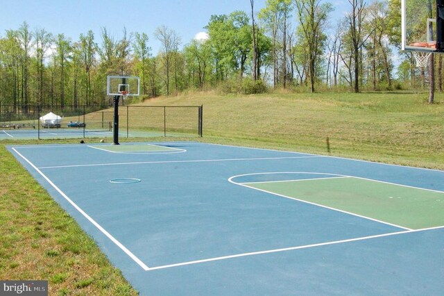 view of basketball court featuring a yard, fence, and community basketball court