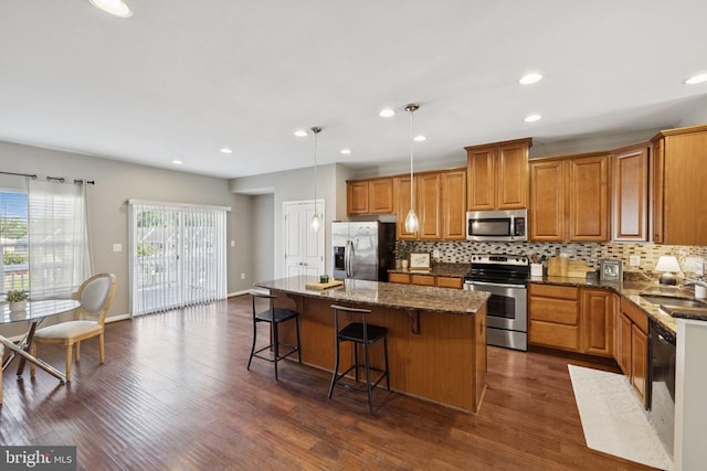 3103 Alliance Ct, Fredericksburg, VA 22408 - kitchen with appliances with stainless steel finishes, a center island, brown cabinetry, backsplash, and dark wood-style flooring
