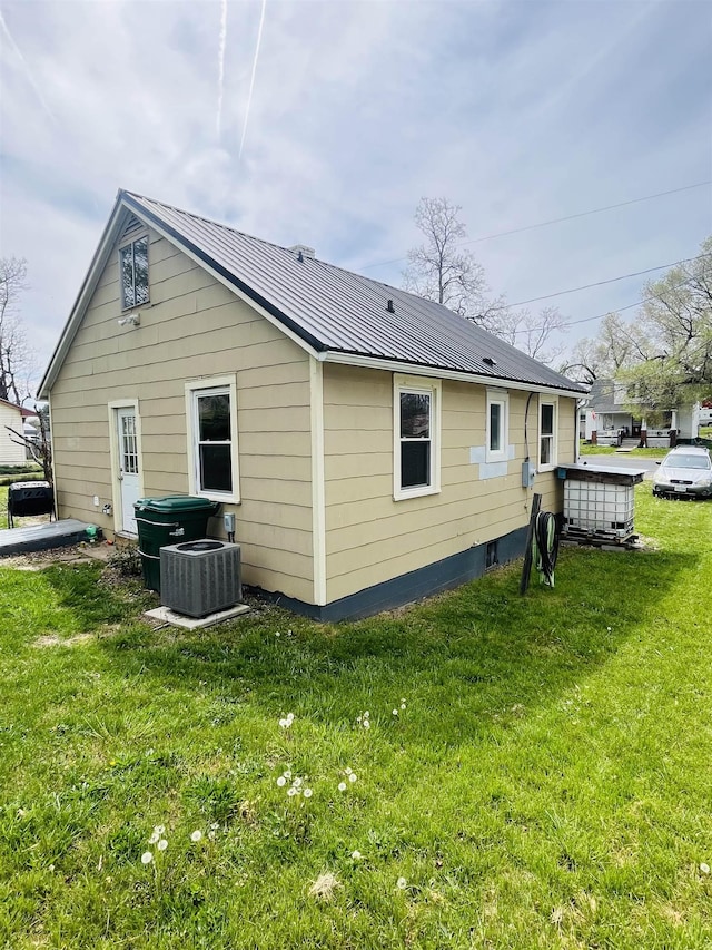 back of property featuring a yard, central AC, and metal roof