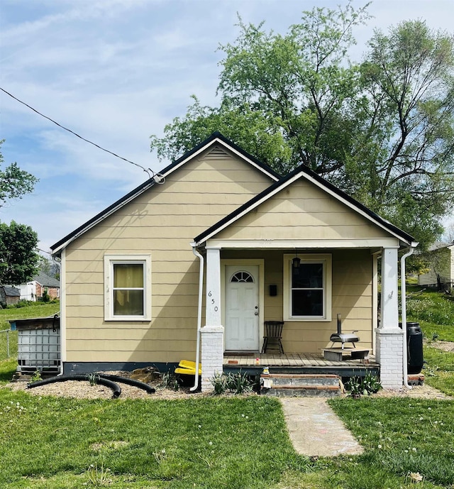 bungalow with central AC unit, a porch, and a front lawn