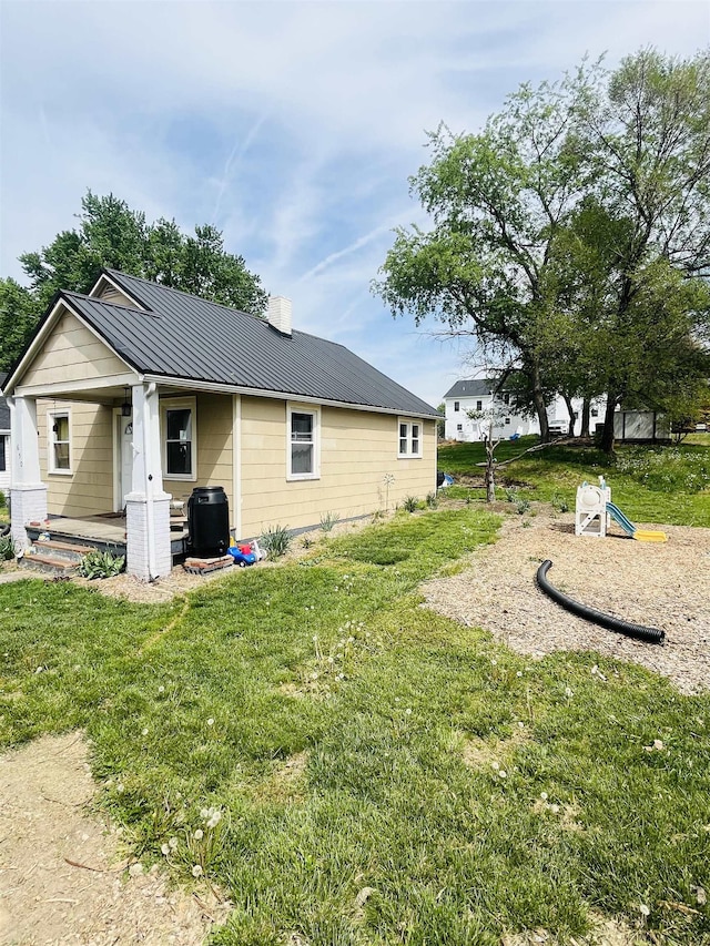 back of property with central AC, a chimney, a standing seam roof, metal roof, and a yard