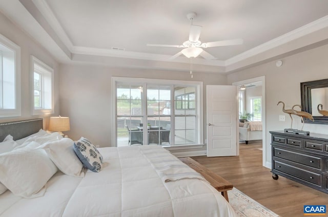 bedroom featuring crown molding, a raised ceiling, visible vents, and wood finished floors