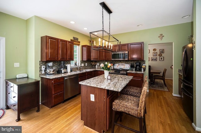 6733 Averett Ct, Fredericksburg, VA 22407 - kitchen with a sink, a kitchen island, light wood-style floors, tasteful backsplash, and appliances with stainless steel finishes