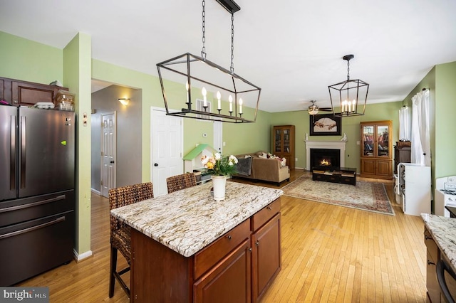 6733 Averett Ct, Fredericksburg, VA 22407 - kitchen featuring freestanding refrigerator, a warm lit fireplace, pendant lighting, a breakfast bar area, and light wood-style floors