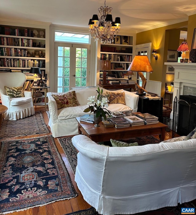 living area with an inviting chandelier, ornamental molding, wood finished floors, and built in features